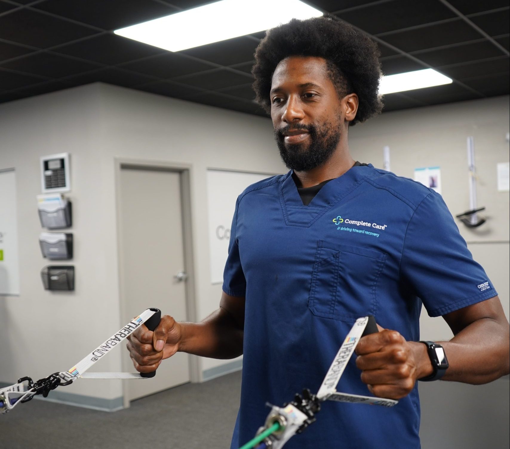 a man wearing a complete care scrub holding a pair of resistance bands
