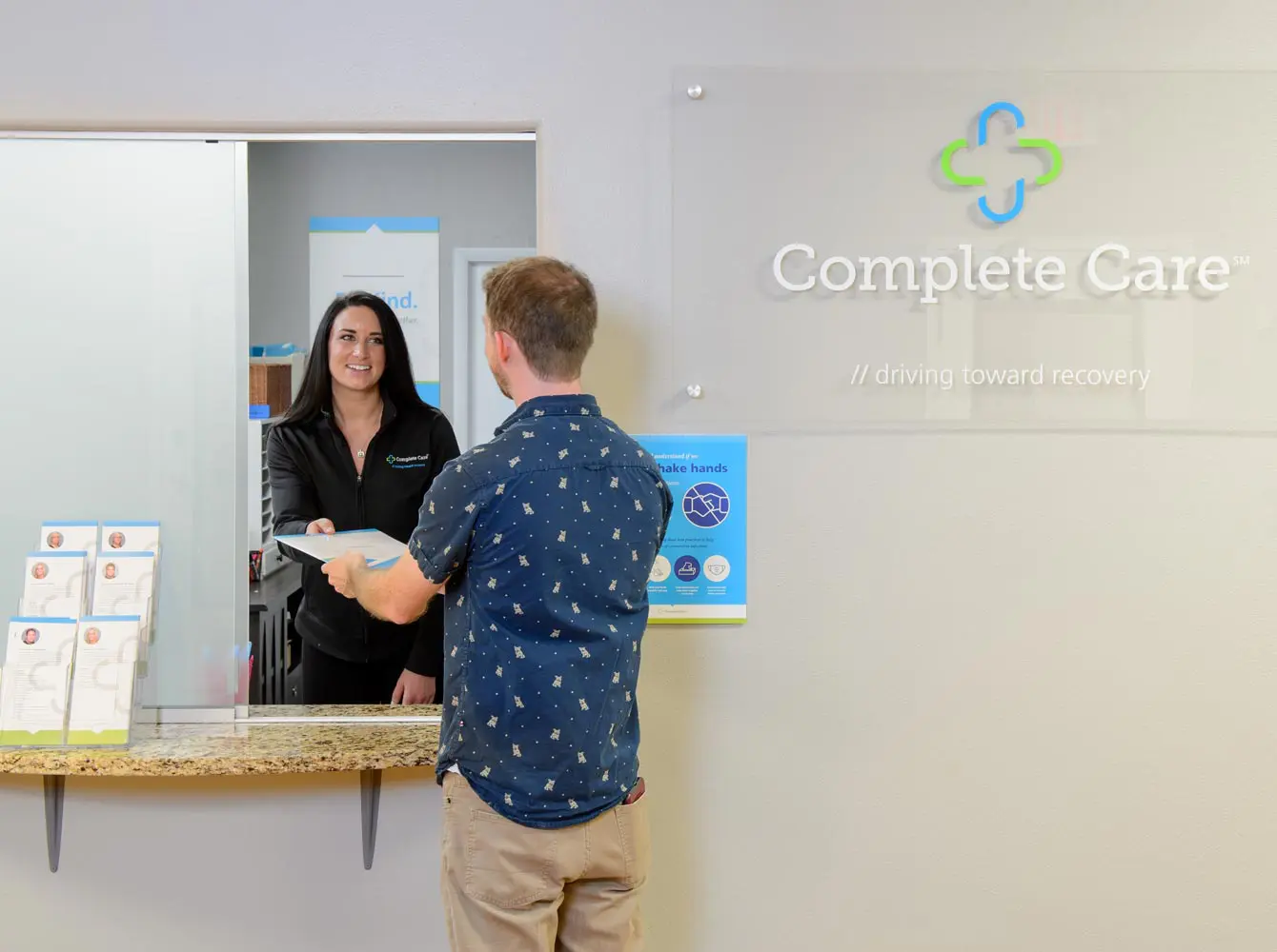 a man is giving forms to a woman in front of a complete care sign